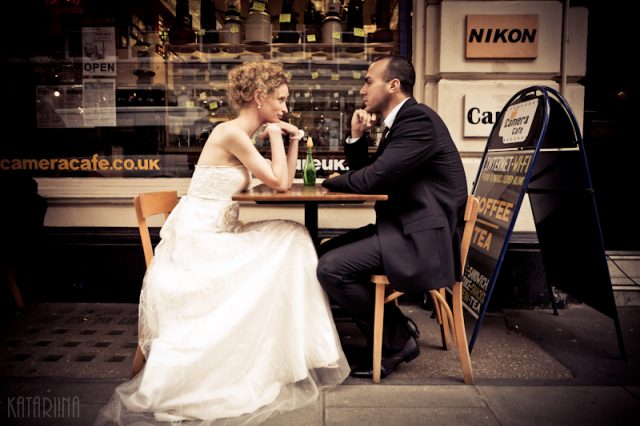 wedding couple sitting at a table in front of camera shop