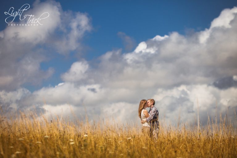 engagement photo in a field with clouds